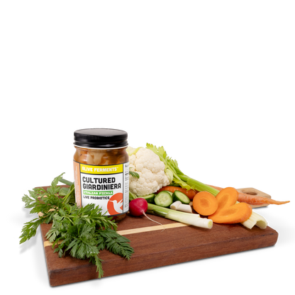A jar of Giardiniera, a traditional Italian Pickle, on a wooden cutting board, surrounded by its ingredients: a colorful medley of fresh vegetables. 